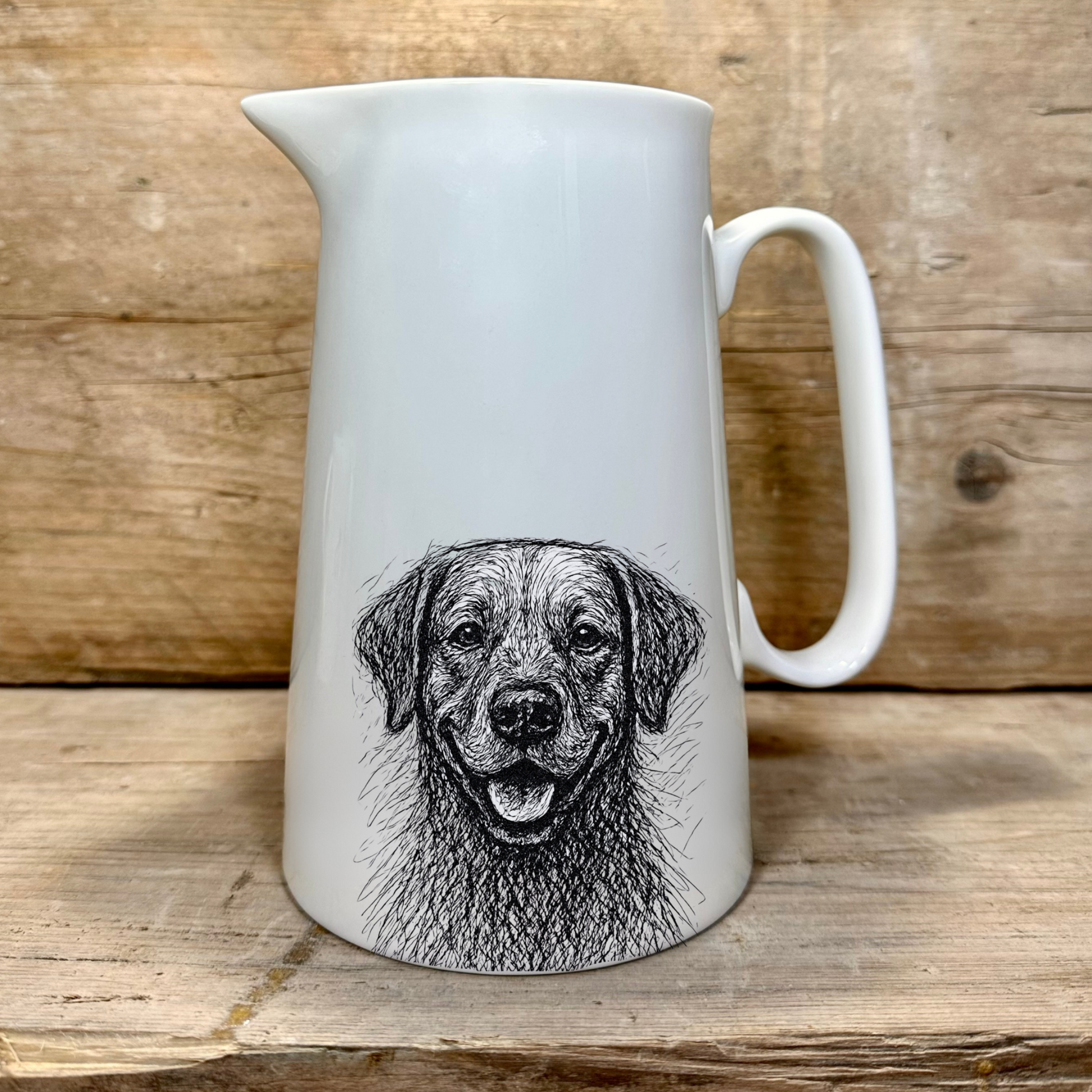 White ceramic jug with a black and white Labrador dog illustration on a wooden surface