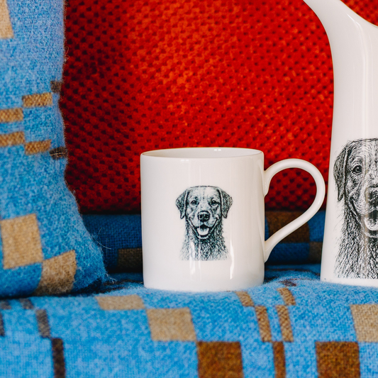 White mug with dog illustration on a colorful fabric background