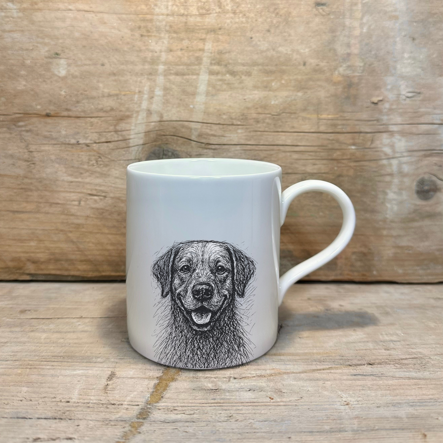 White mug with a black and white dog illustration on a wooden surface